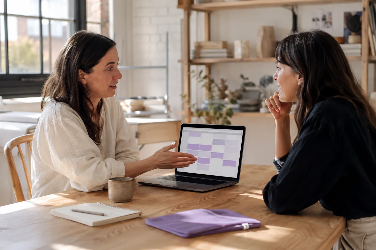 Two colleagues discussing an upcoming meeting in a sunlit studio.